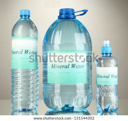 Different water bottles with label on grey background
