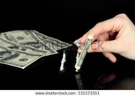 Cocaine drugs lines and female hand holding rolled dollar banknote, close up