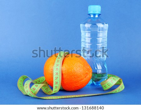 Orange with measuring tape, bottle of water, on color background