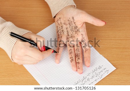Write cheat sheet on hand on wooden table close-up