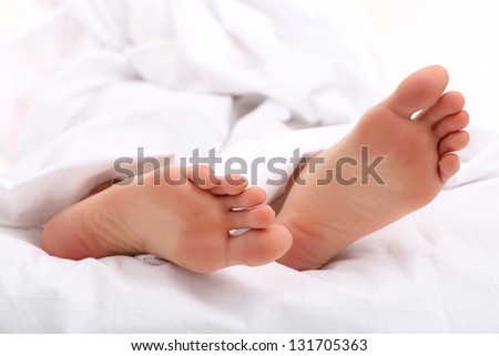 Beautiful feet of a young woman lying in bed close up
