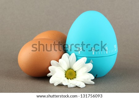 Blue egg timer and eggs, on color background