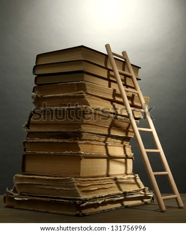 Old books and wooden ladder, on grey background