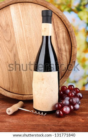 Composition of corkscrew and bottle of wine, grape, wooden barrel  on wooden table on bright background