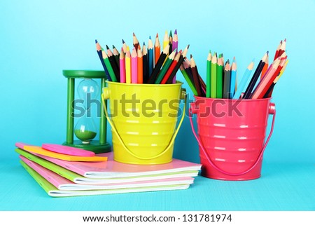 Colorful pencils with school supplies on blue background
