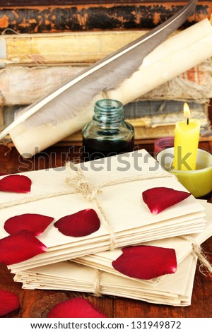 Stacks of old letters with dried rose petals on wooden table