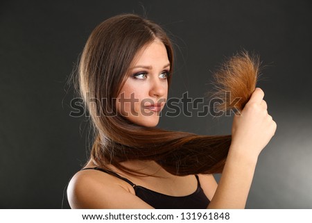 Beautiful woman holding split ends of her long hair,  on black background