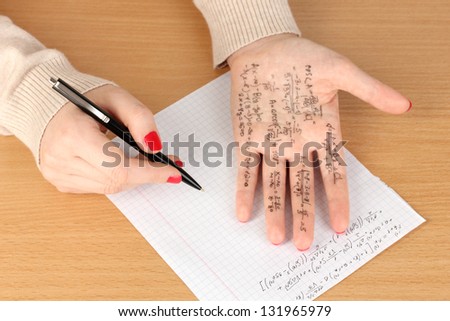 Write cheat sheet on hand on wooden table close-up