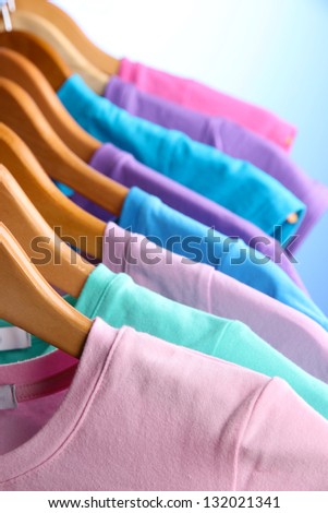 Lots of T-shirts on hangers on blue background