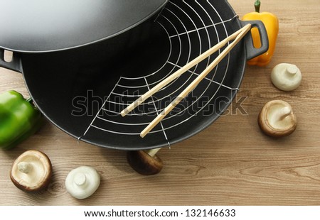 Black wok pan and vegetables on kitchen table, close up