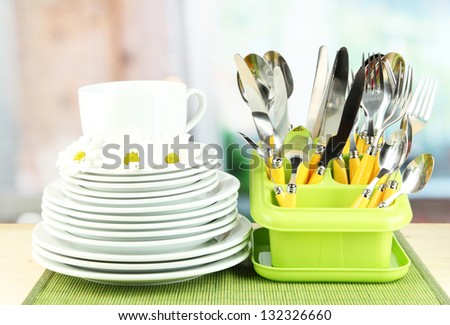 Plates, forks, knives, spoons and other kitchen utensil on bamboo mat, on bright background