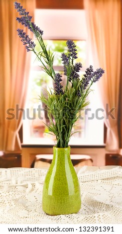 Decorative ceramic vase with lavender on wooden table on window background
