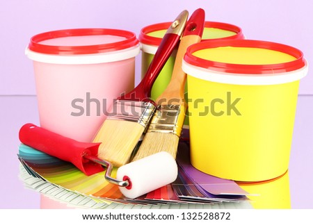 Set for painting: paint pots, brushes, paint-roller, palette of colors on lilac background