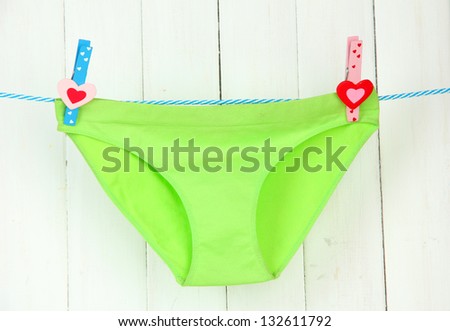 Womans panties hanging on a clothesline, on white wooden background