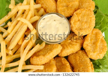 Fried chicken nuggets with french fries and sauce close-up