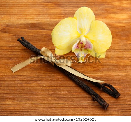 Vanilla pods with flower, on brown wooden background