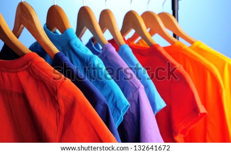 Lots of T-shirts on hangers on blue background