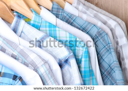 Men\'s shirts on hangers on wooden background