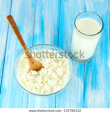 Glass of milk and cheese on blue wooden table