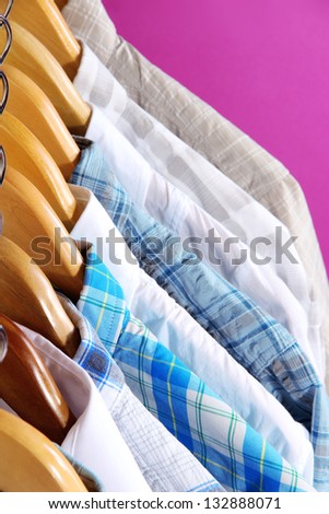 Men\'s shirts on hangers on purple background