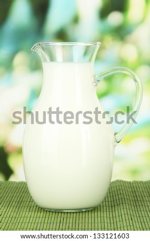 Pitcher of milk on table on bright background
