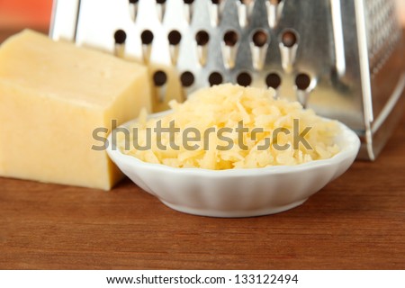 Metal grater and cheese, on bright background