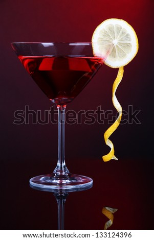 Red cocktail in martini glass on dark red background