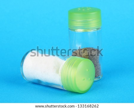 Salt and pepper shakers on color background