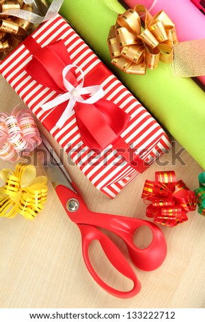 Rolls of Christmas wrapping paper with ribbons, bows on wooden background