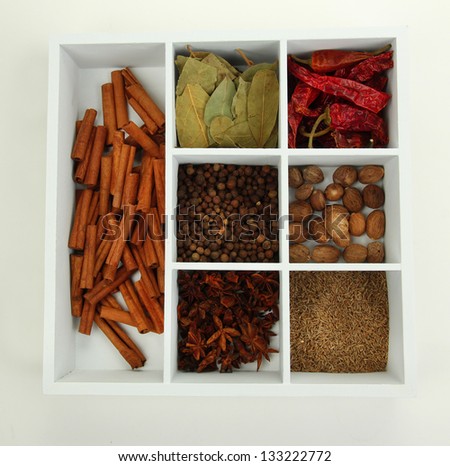 Assortment of aroma spices in white wooden box isolated on white