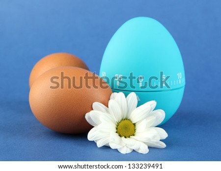Blue egg timer and eggs, on color background