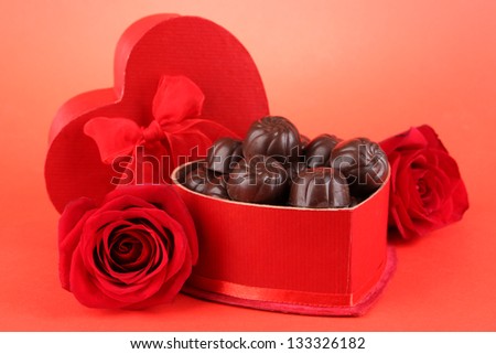 Chocolate candies in gift box, on red background