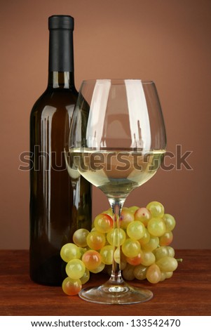 Composition of wine bottle, glass of white wine, grape on color background