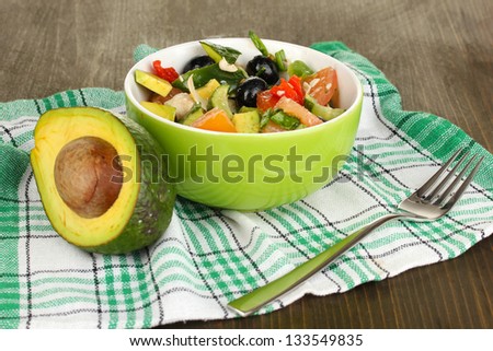 Tasty avocado salad in bowl  on wooden table close-up