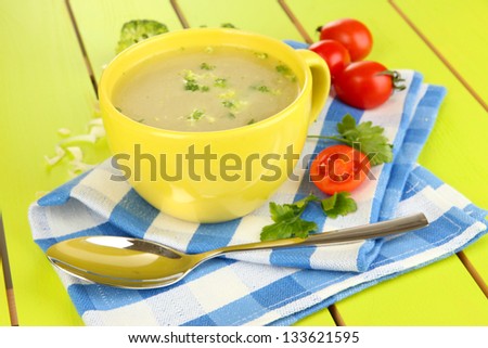 Diet soup with vegetables in cup on green wooden table close-up