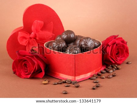 Chocolate candies in gift box, on brown background