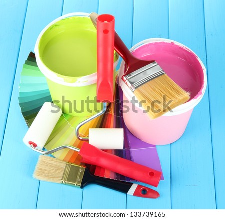 Set for painting: paint pots, brushes, paint-roller on blue wooden table