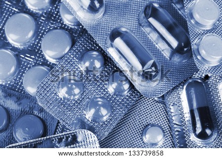 Capsules and pills packed in blisters in grey light