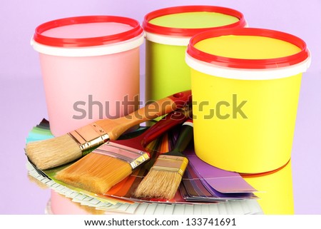 Set for painting: paint pots, brushes, palette of colors on lilac background