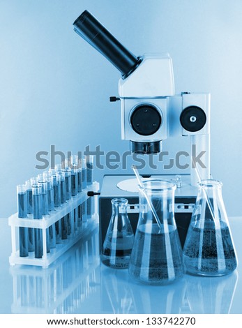 Test tubes with colorful liquids and microscope in blue light