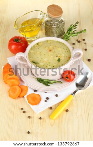 Nourishing soup in pink pan with ingredients on wooden table close-up