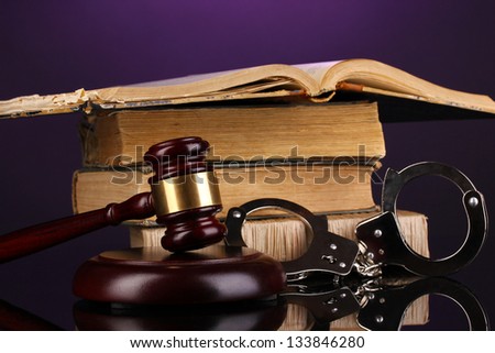Gavel, handcuffs and books on law on purple background