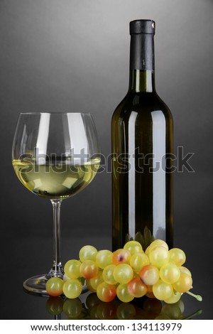 White wine glass and bottle of wine on grey background