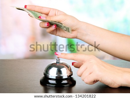 Female hand ringing in service bell on bright background
