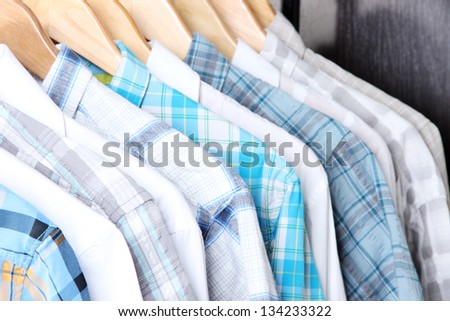 Men\'s shirts on hangers on wooden background