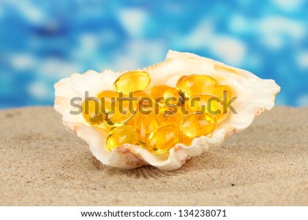fish oil in the shell in the sand on a blue background