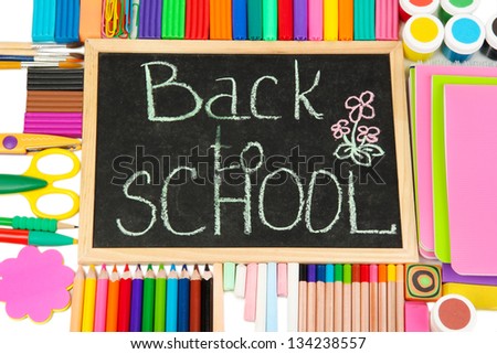 The words \'Back to School\' written in chalk on the small school desk with various school supplies close-up