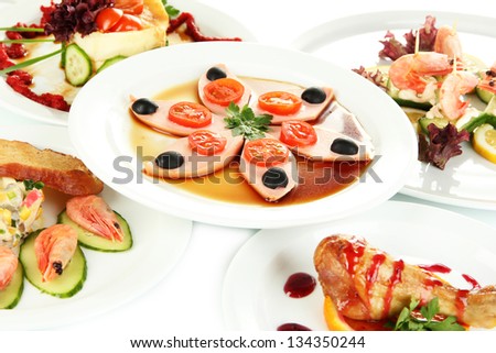 Small portions of food on big white plates close up