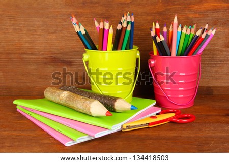 Colorful pencils with school supplies on wooden background