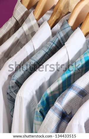 Men\'s shirts on hangers on purple background